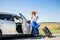 Pretty girl with suitcase standing near car and wiat for her dreaming trip