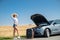 Pretty girl with suitcase standing near car and wiat for her dreaming trip