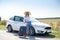 Pretty girl with suitcase standing near car and wiat for her dreaming trip