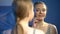 Pretty girl touching facial skin near mirror, satisfied with reflection, beauty