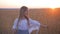 Pretty girl walk across the wheat field. Happy young girl running in the field at sunset. Freedom concept.