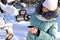 pretty girl in warm clothes pours tea into mug from thermos in winter forest. Outdoor recreation on frosty sunny day.