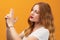 Pretty girl with wavy redhead holding symbolic gun with hand gesture