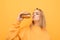 Pretty girl in yellow clothes holds a burger and kisses. Portrait of a hungry girl on a yellow background with a tasty burger,