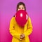 Pretty girl in yellow coat with red air balloon in hands