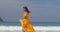 Pretty girl in yellow long dress walking along the sea, waves and the wind blew her hair and a light skirt