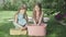 Pretty girls in dresses washing ducks in water outdoors. Wide shot portrait of charming joyful Caucasian twin sisters