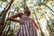 Pretty glamorous young woman with blond hair in a fashionable striped pink dress posing on the background of a trees