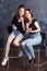 Pretty happy teenage girls with donuts  siting on chairs and having fun. Portrait of joyful smiling girls with donuts on black