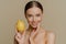 Pretty healthy European woman uses lemon for making natural face mask takes care of her body and skin stands topless