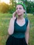 Pretty hipster girl speaking on mobile phone. Woman in green shirt and bandana standing on blurred nature background