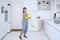 Pretty housekeeper dancing with a broom in kitchen