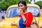 Pretty Indian/asian young girl eating Ice Cream in cone, standing near ice cream shop or taxi