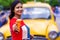 Pretty Indian/asian young girl eating Ice Cream in cone, standing near ice cream shop or taxi