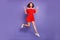 Pretty jumping high lady showing v-sign symbols wear red dress isolated purple background