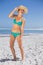 Pretty laughing woman in bikini on beach wearing sunhat