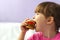 A pretty little baby with a hamburger in her hands. A little girl is jokingly biting a children`s toy burger. Close-up of a child