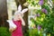 Pretty little boy wearing bunny ears hunting for easter eggs in spring park on Easter day