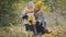 Pretty little daughter with her mommy plays with yellow leaves in autumn park