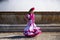 A pretty little girl dancing flamenco dressed in a white dress with pink frills and fringes in a famous square in seville, spain.