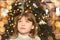 pretty little girl in a dress waiting at the foot of the Christmas tree for the opening of presents