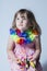 Pretty little girl dressed in pink floral dress and silk flower garland sitting on stool