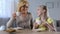 Pretty little girl drinking tea with her nanny and happily smiling, traditions