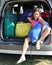 Pretty little girl fills the suitcases on the car