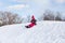 Pretty little girl in her ski suit screaming of joy while sliding down a small snow