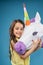Pretty little girl hugging white 3D unicorn head.