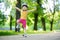 Pretty little girl learning to skateboard on beautiful summer day in a park