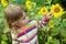 Pretty Little Girl looks at sunflower in garden