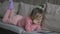 Pretty little girl lying on sofa using tablet . Small child playing on the laptop on an orange couch at home. A little