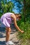 Pretty little girl with a mask to protect herself from the coronavirus picking a flower on a path surrounded by nature