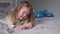 Pretty little girl playing with little christmas trees lying on bed in gray bedroom. new year, childhood, daughter