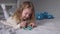 Pretty little girl playing with little christmas trees lying on bed in gray bedroom. new year, childhood, daughter