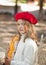 Pretty little girl in a red cap sitting in outdoor cafe with baguette and smiling. French style