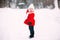 Pretty little girl in red coat in winter forest. Little girl having fun on winter day