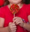 Pretty little girl in red dress holding a lollipop hard caramel in a hands