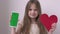 Pretty little girl shows phone with green screen mock up cellphone, mobile, telephone and red heart. Chroma key green