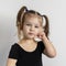 pretty little girl with two ponytails is standing in a pensive pose