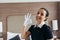 Pretty maid in white glove showing okay sign and looking at camera in hotel room