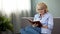 Pretty mature female sitting on sofa and reading self-development book, hobby