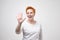 Pretty mature woman with red hair in white t-shirt showing 5 or five fingers hand gesture