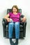 Pretty middle-age woman sitting up right in black leather recliner armchair. Checking blood pressure using portable blood pressure