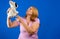 Pretty middle-aged woman playing with a stuffed puppy on blue studio background