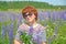 A pretty middle-aged woman in sunglasses stands among flowering lupins