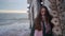 Pretty mixed ethnic woman standing, leaning on old flooded wooden house, chapel washed by sea waves, sinking in water at