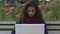 Pretty mixed race lady opening laptop and chatting with boyfriend at park