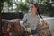 Pretty model posing on bench with cushions in the outdoor cafe, dark-haired beauty holds her hair plait in one hand